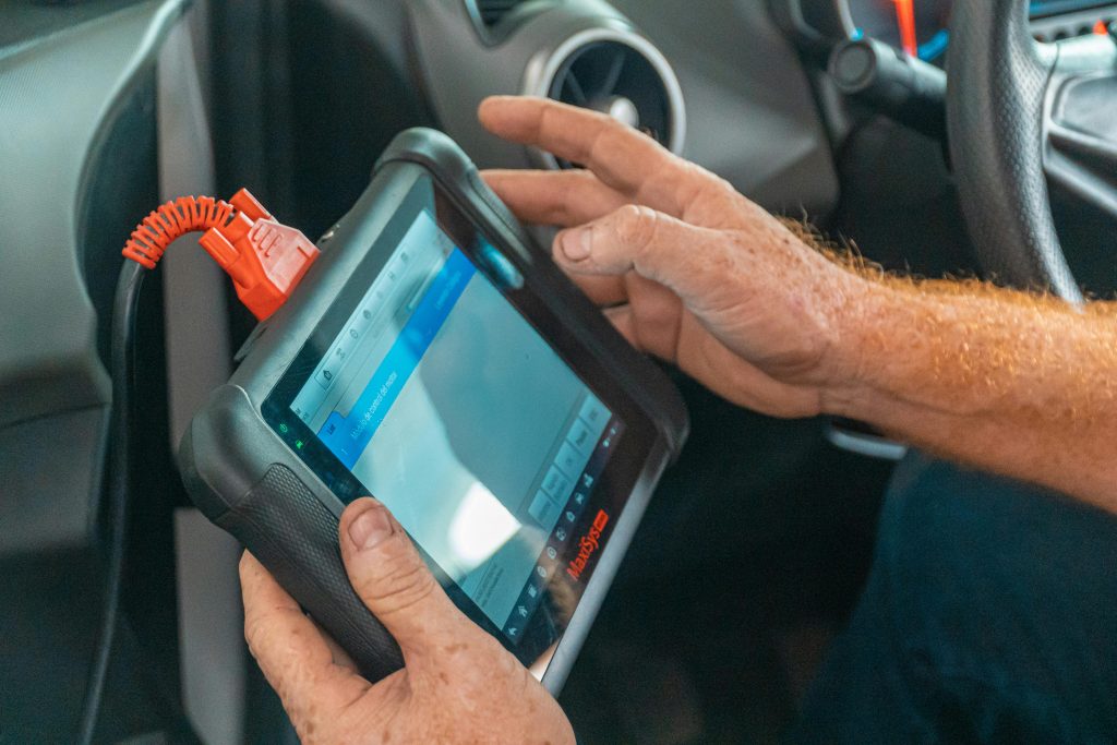 A mechanic uses a diagnostic tablet inside a car for vehicle analysis.